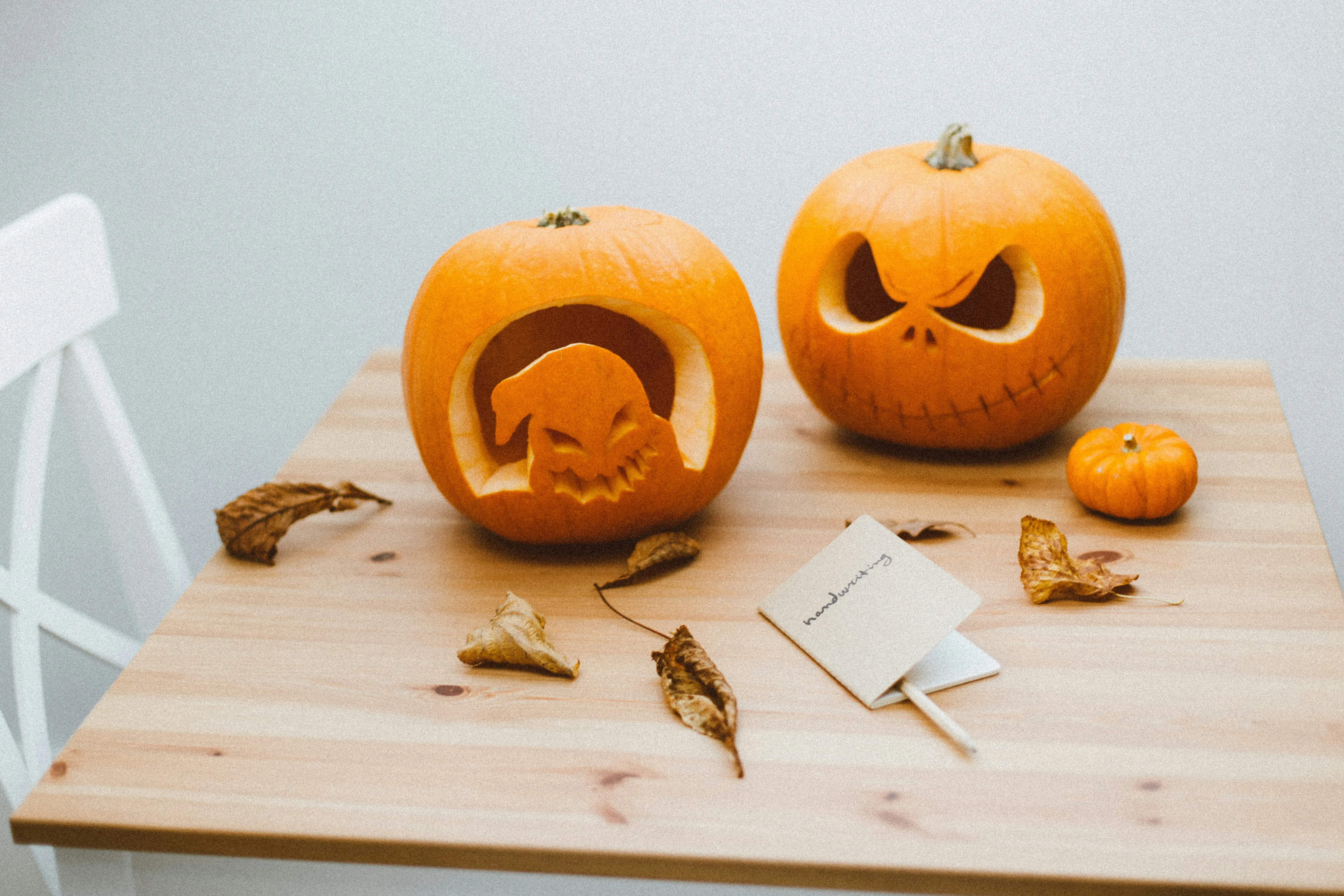 Funny Carved Pumpkins on Wooden Table in White Room Image