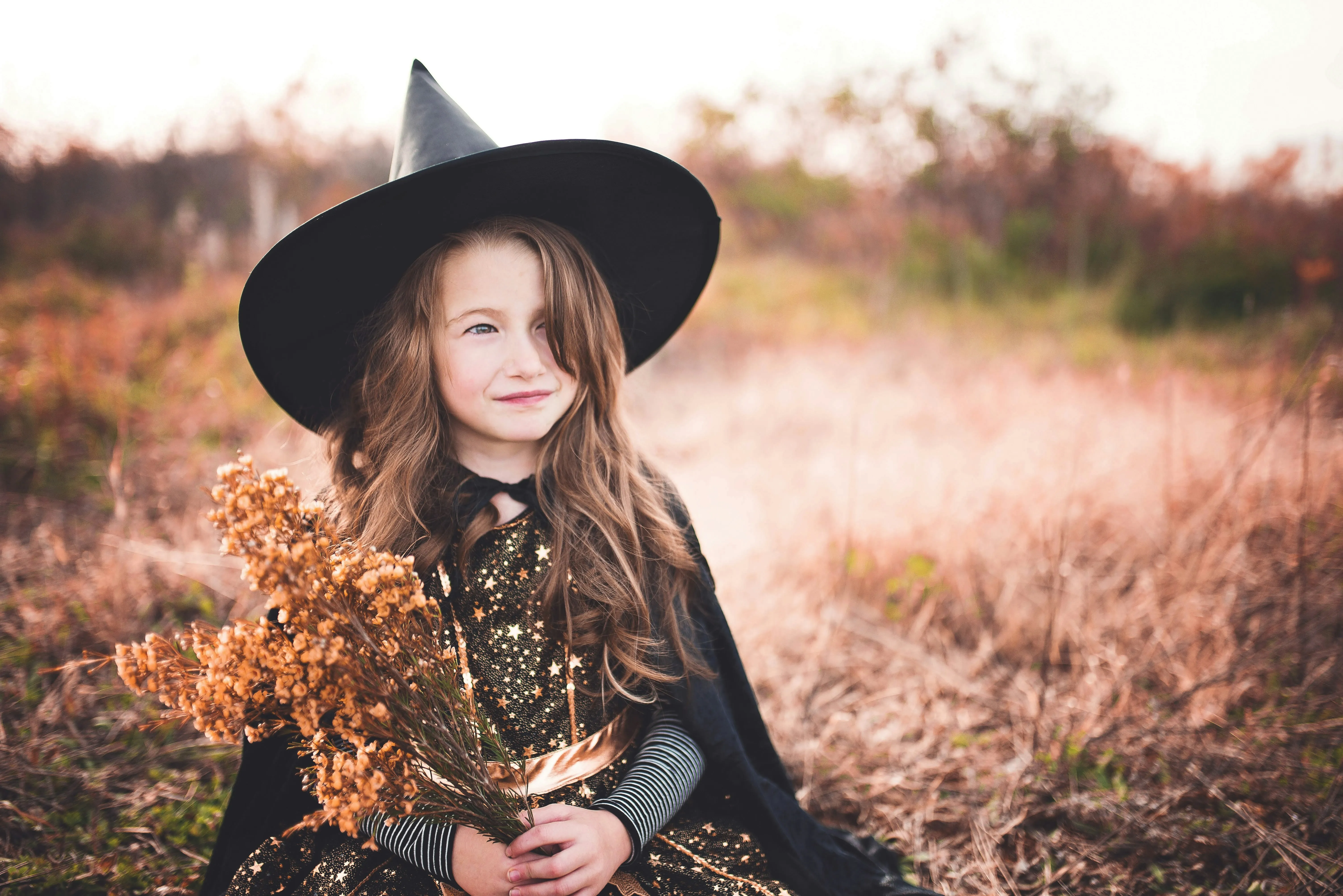 Girl Wearing Witch Hat and Black Dress in Field Wallpaper