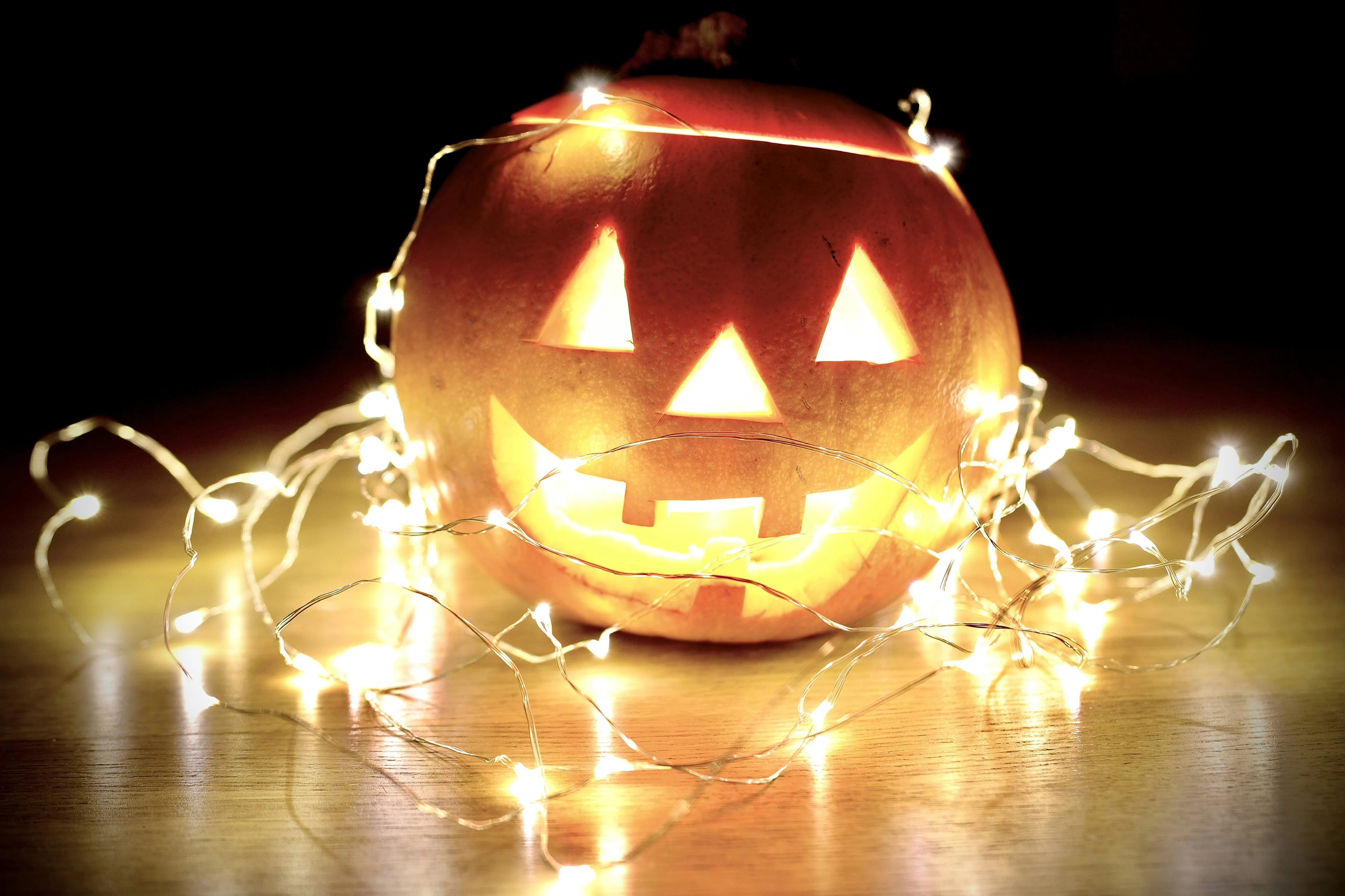 Glowing Halloween Pumpkin Surrounded By Lights Wallpaper