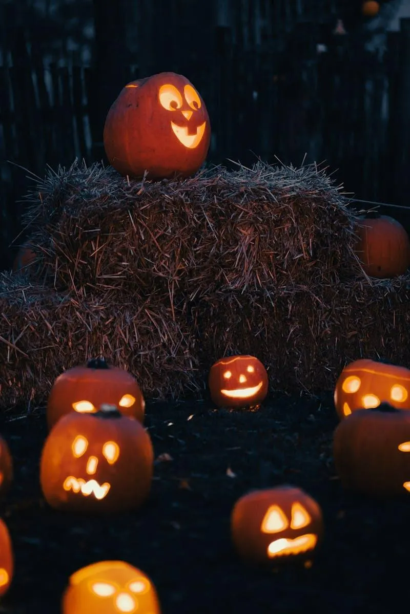 Glowing Jack O Lanterns on Hay Bale in Dark Halloween Night