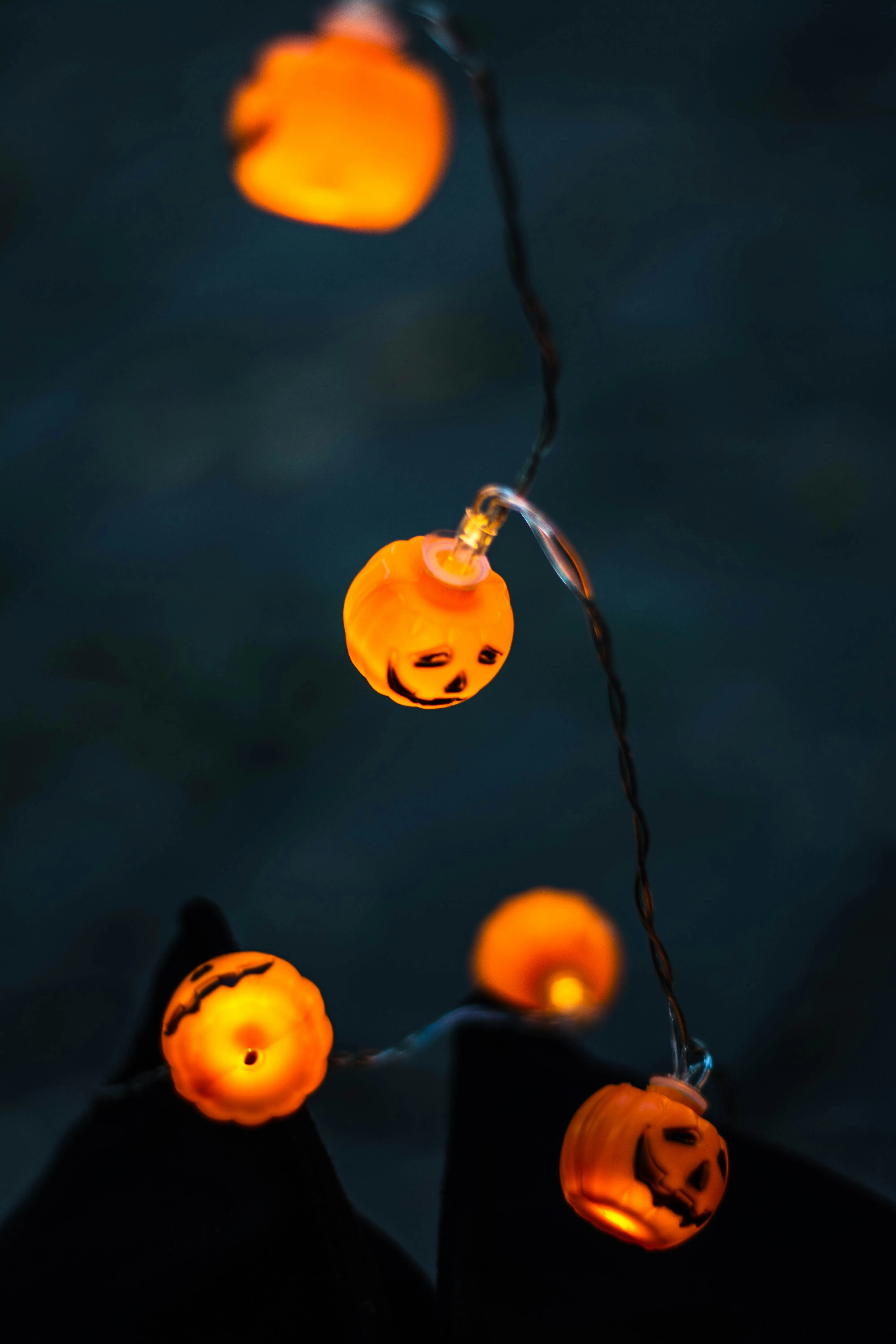 Glowing Pumpkin String Lights Hanging in Dark Wallpaper
