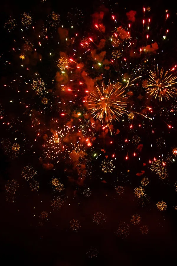 Golden and Red Fireworks Exploding over a City Landscape