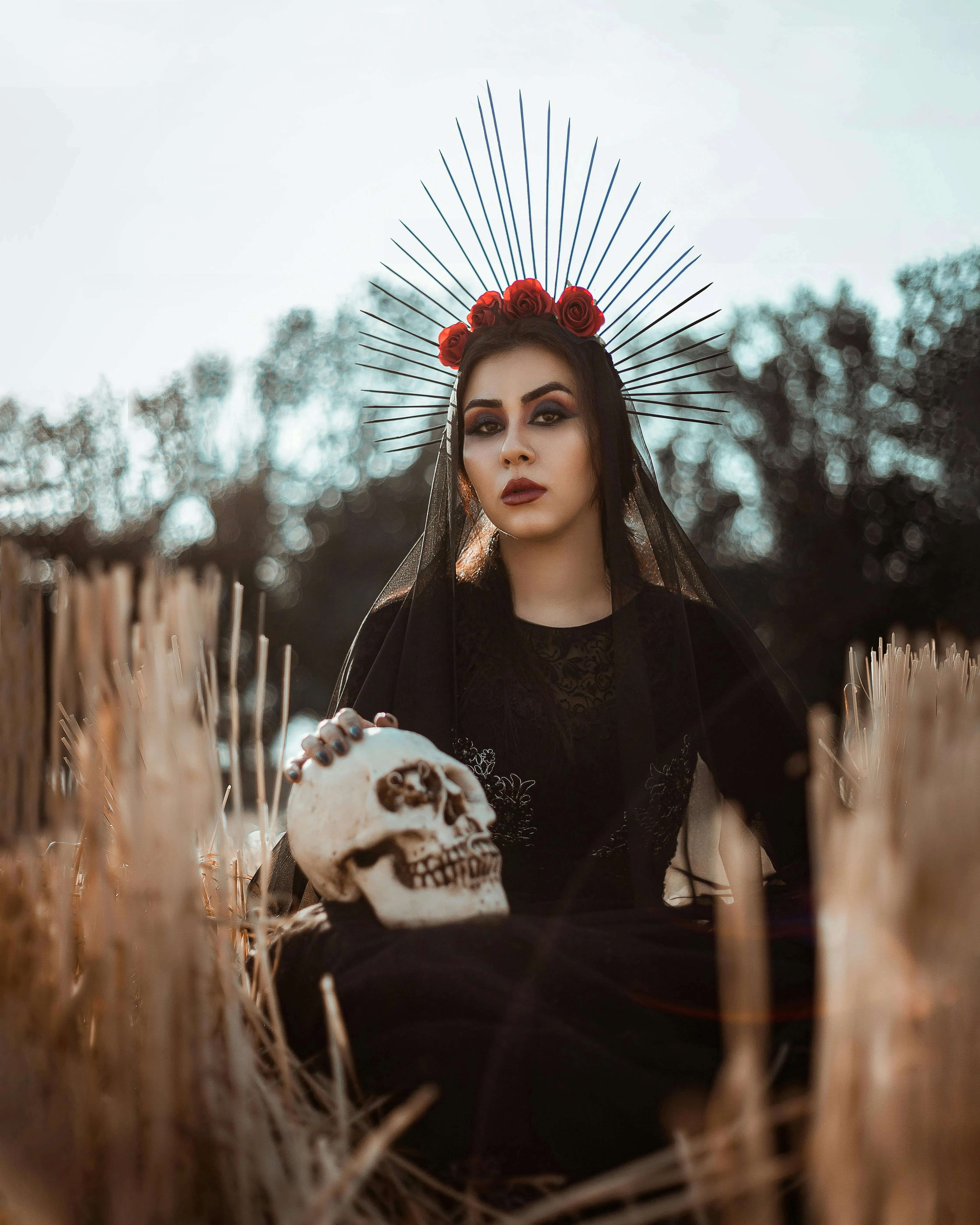 Gothic Girl Holding Skull in Autumn Field Setting Wallpaper
