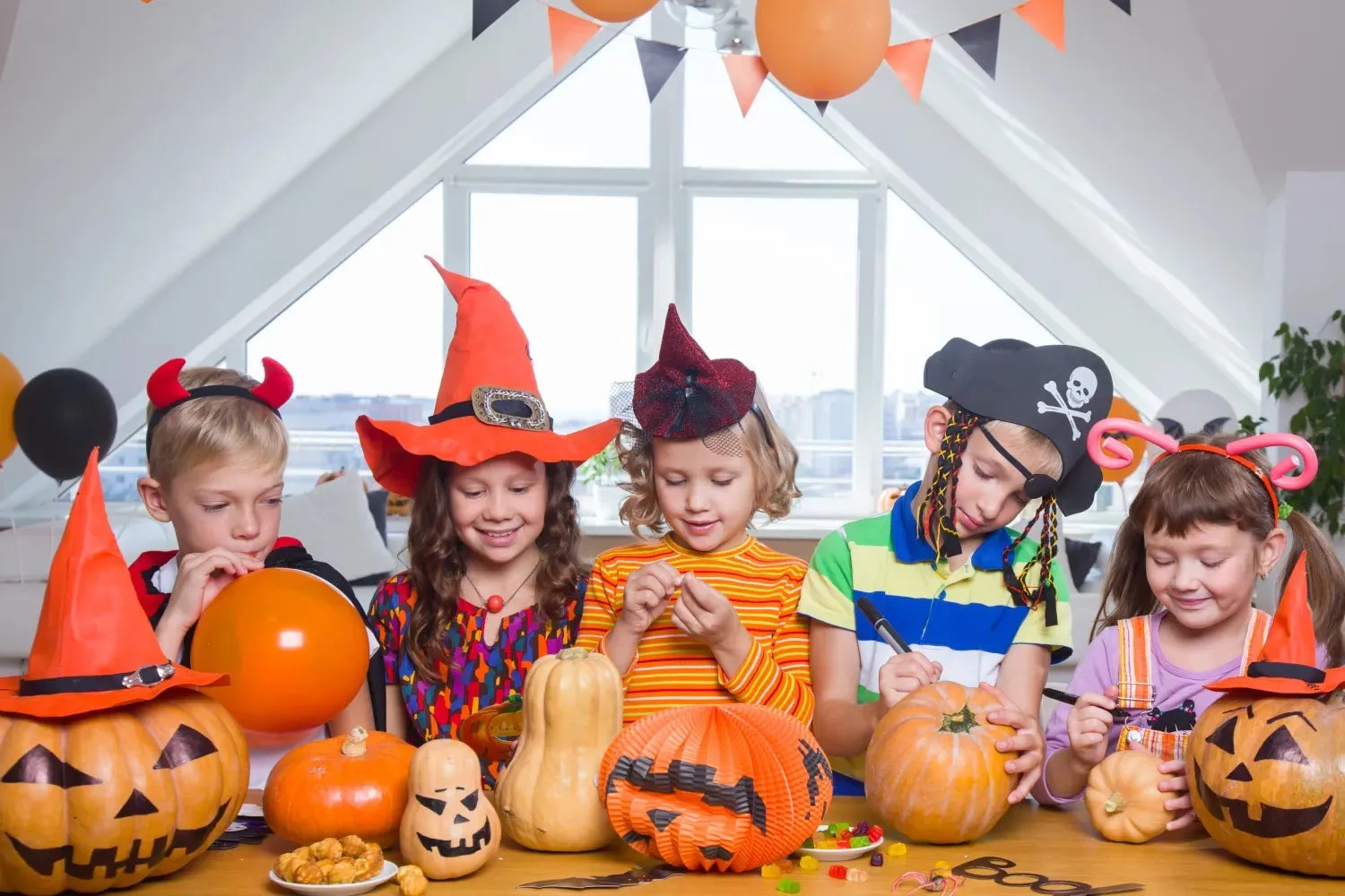Group of Kids Wearing Halloween Costumes with Pumpkins Indoors