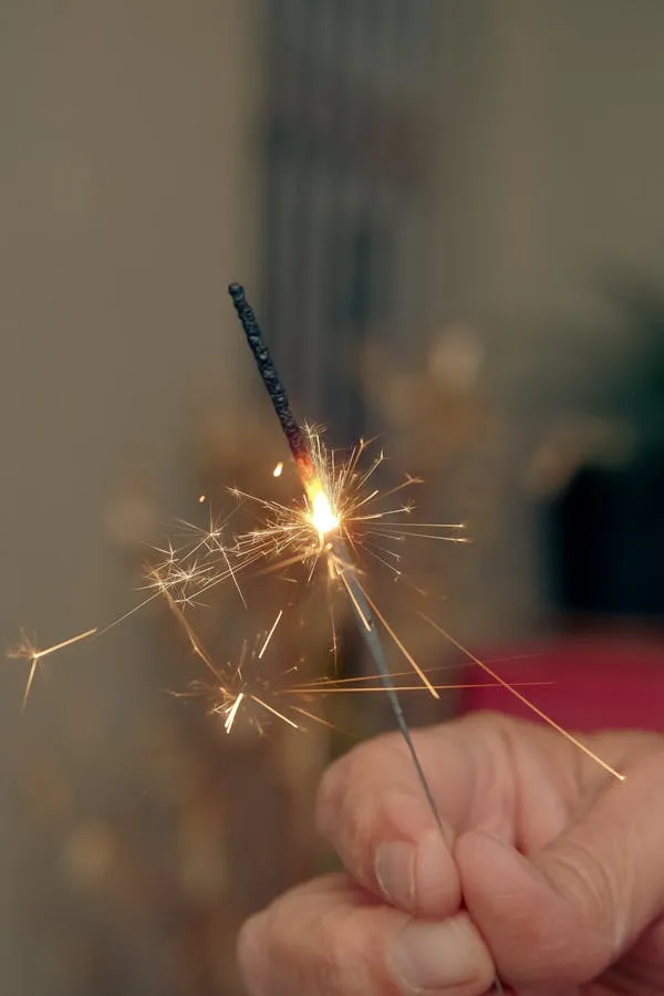 Hand Holding Sparkler Creating Glowing Trails at Night