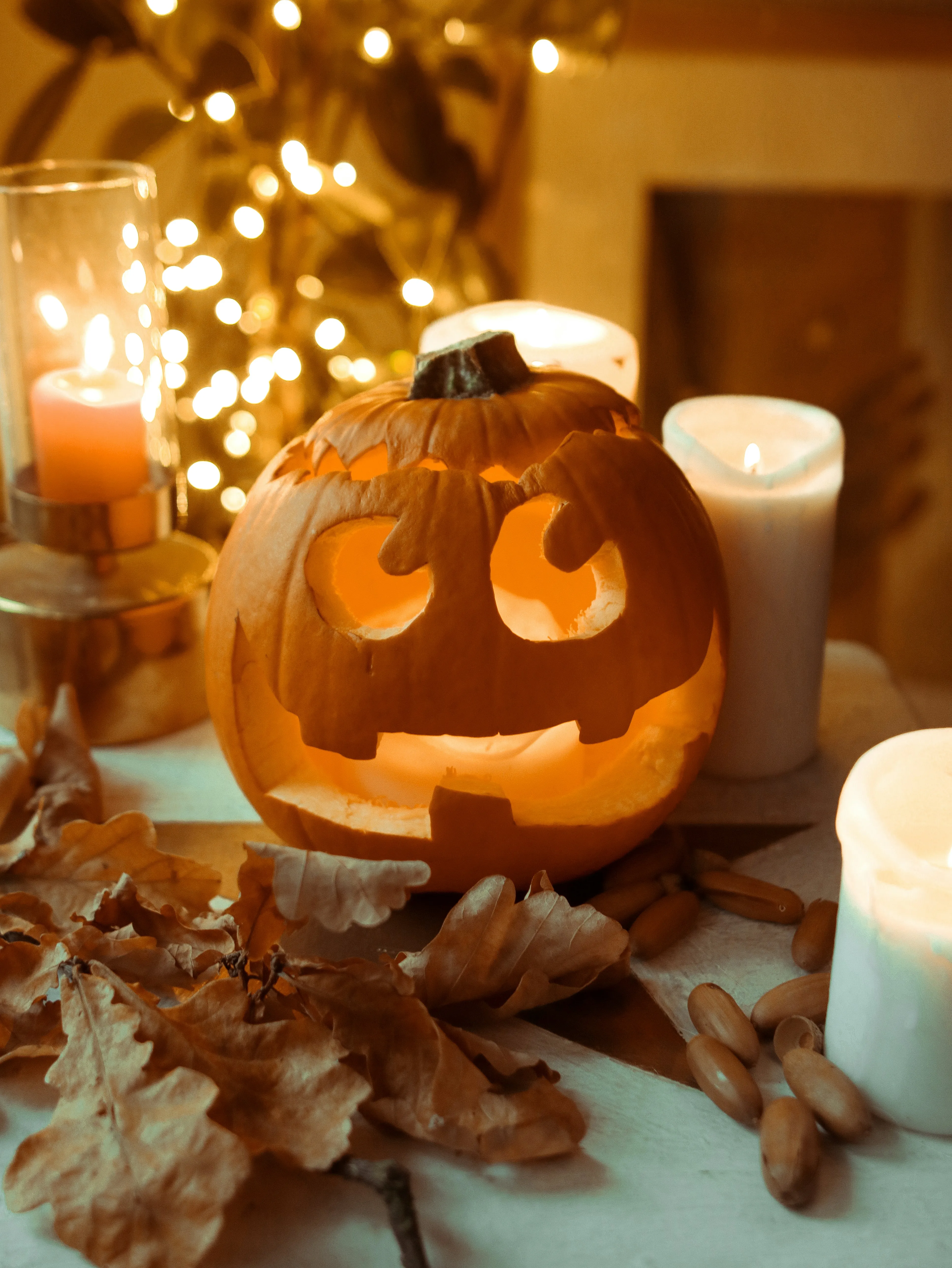 Happy Carved Pumpkin Surrounded By Autumn Candles Wallpaper