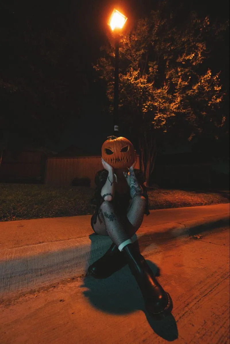 Individual in Halloween Costume Kneeling on a Dark Road