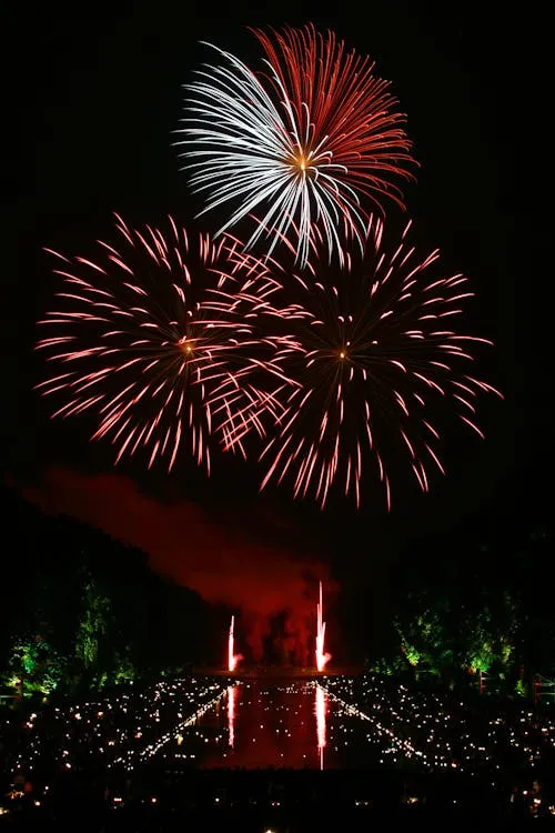 Intense Red Fireworks Erupting from a Park with Reflections