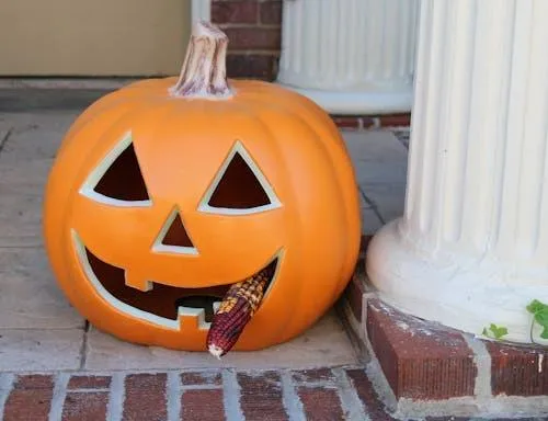 Jack O Lantern Pumpkin By White Column on Porch with Corn