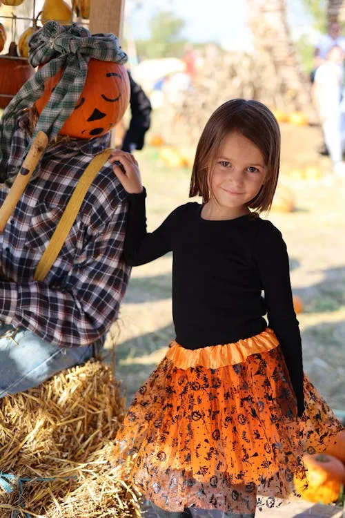 Kid Standing near the pumpkin head Scarecrow image