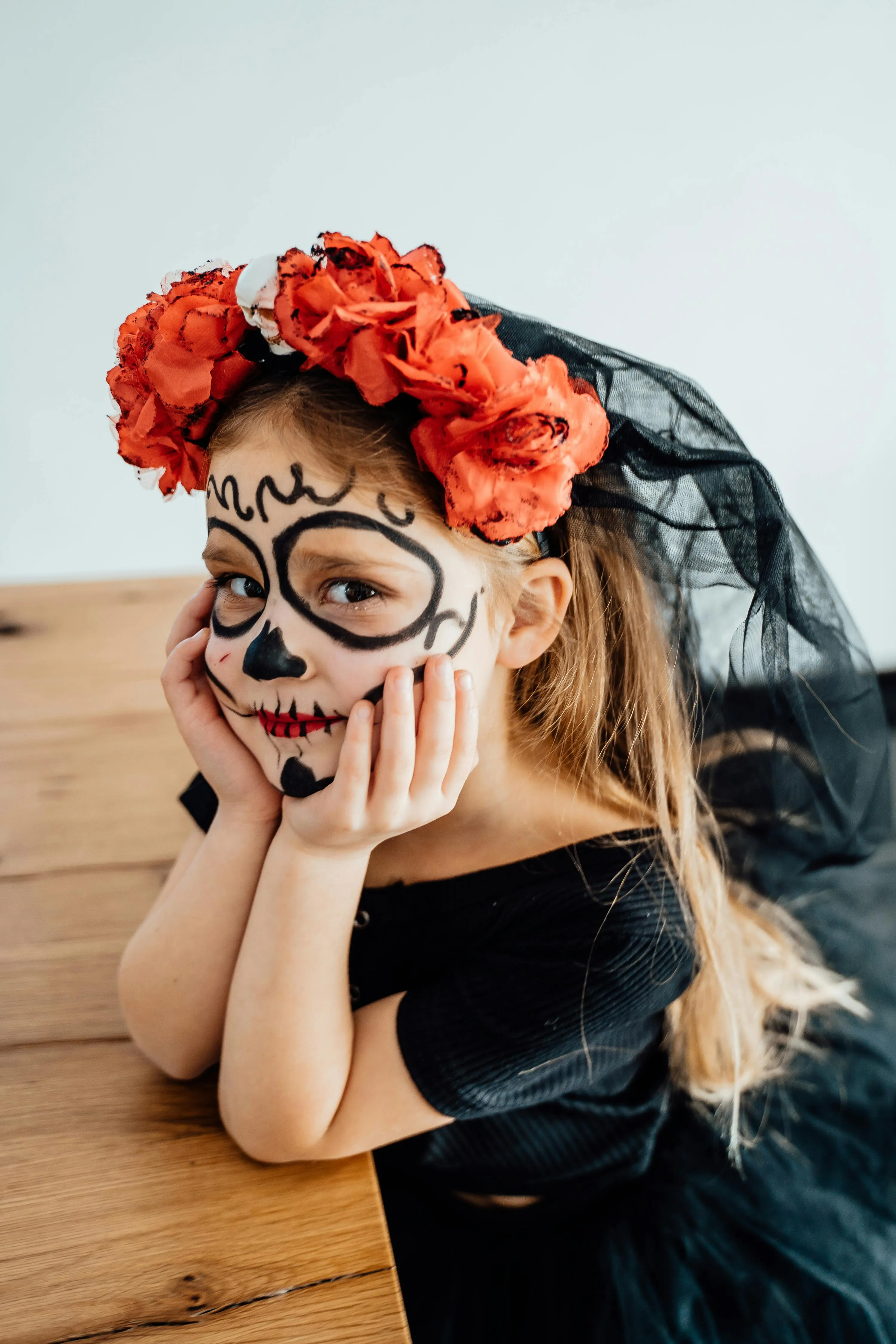 Kid with Red Floral Headpiece Wearing Halloween Makeup
