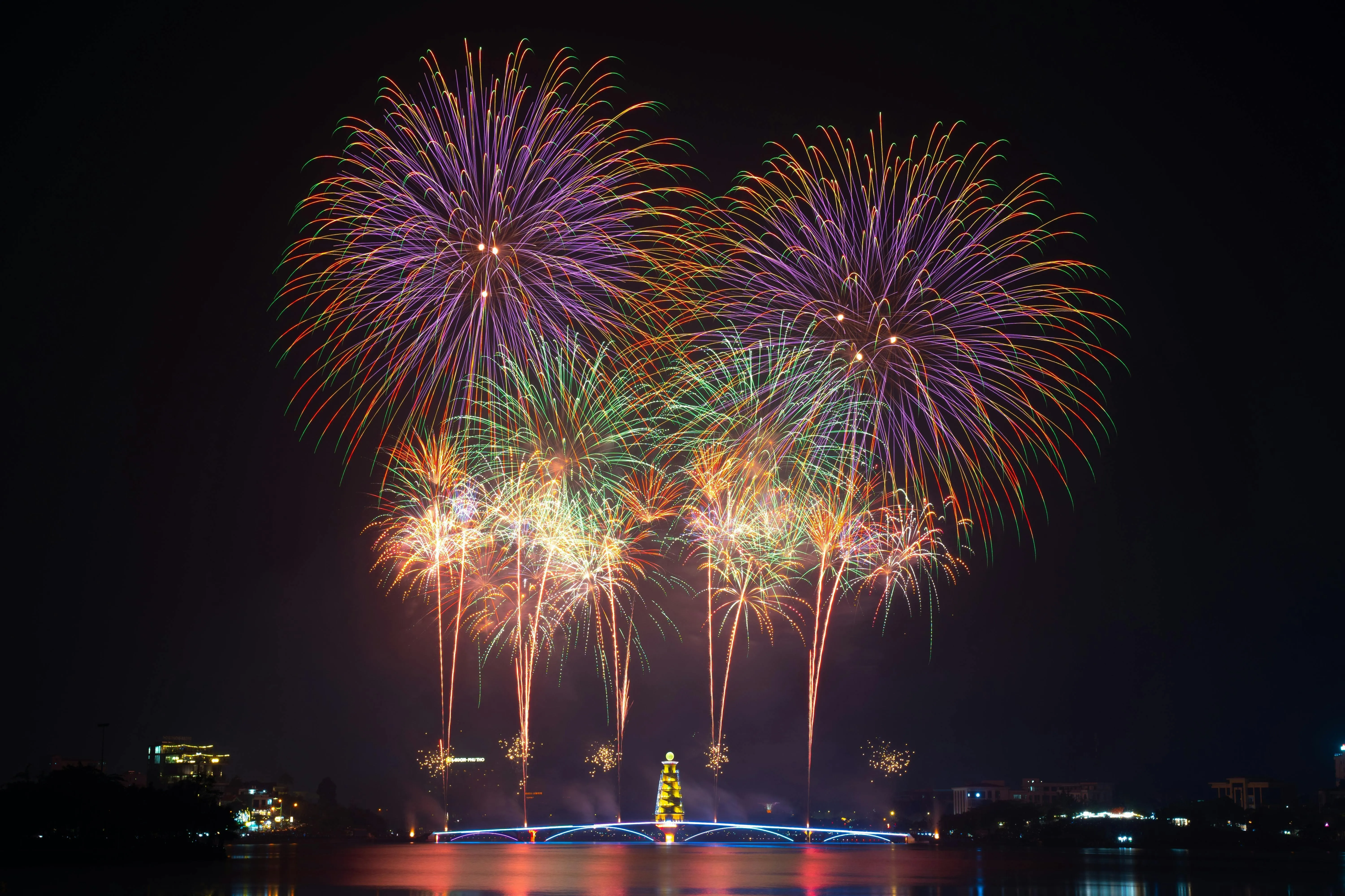 Large burst of fireworks over a city with buildings in distance