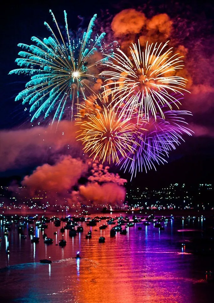 Large fireworks above boats and reflections on water