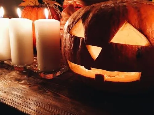 Lit Pumpkin and Candles on Wooden Table Creating Cozy Ambiance