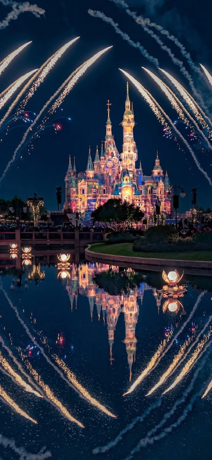 Magical fireworks display at a castle with bright reflections