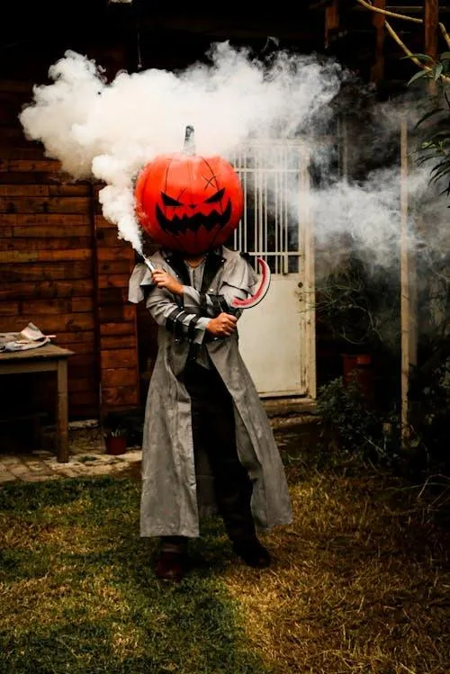 Man in Dark Costume with Pumpkin Head and Smoke Effect