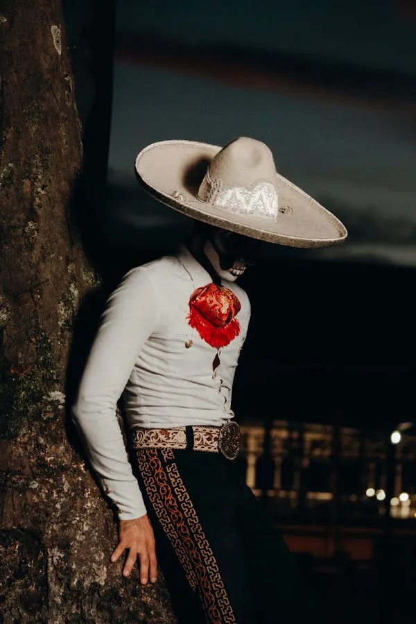 Man in Day of the Dead costume leaning against tree