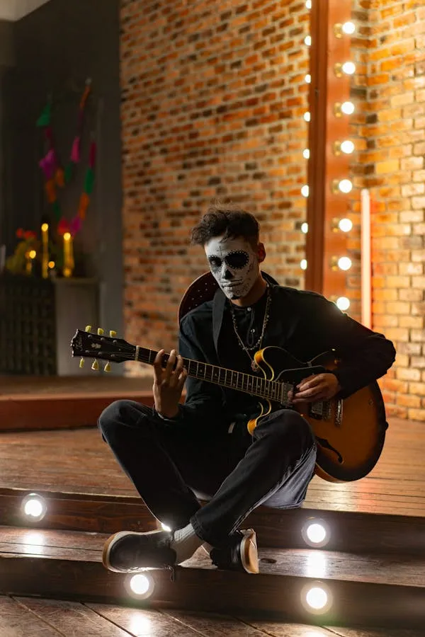 Man in Skull Makeup Playing Guitar with Festive Lights image