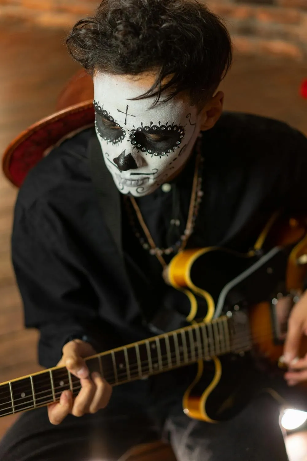 Man Playing Guitar with Skull Makeup for Halloween Celebration