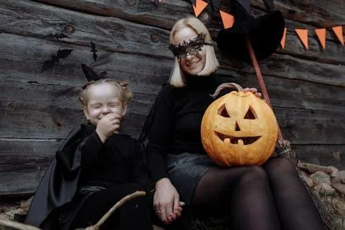 Mother and Child in Witch and Pumpkin Costumes HD image