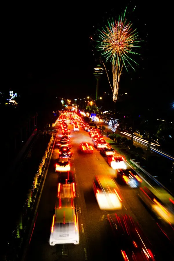 Nighttime fireworks with car lights on the busy street below