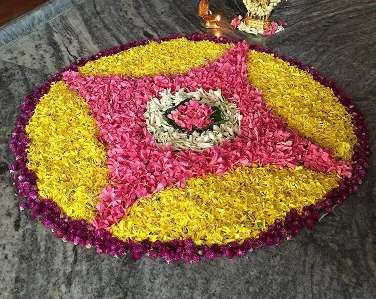 Onam circular pookolam with flower borders on the floor