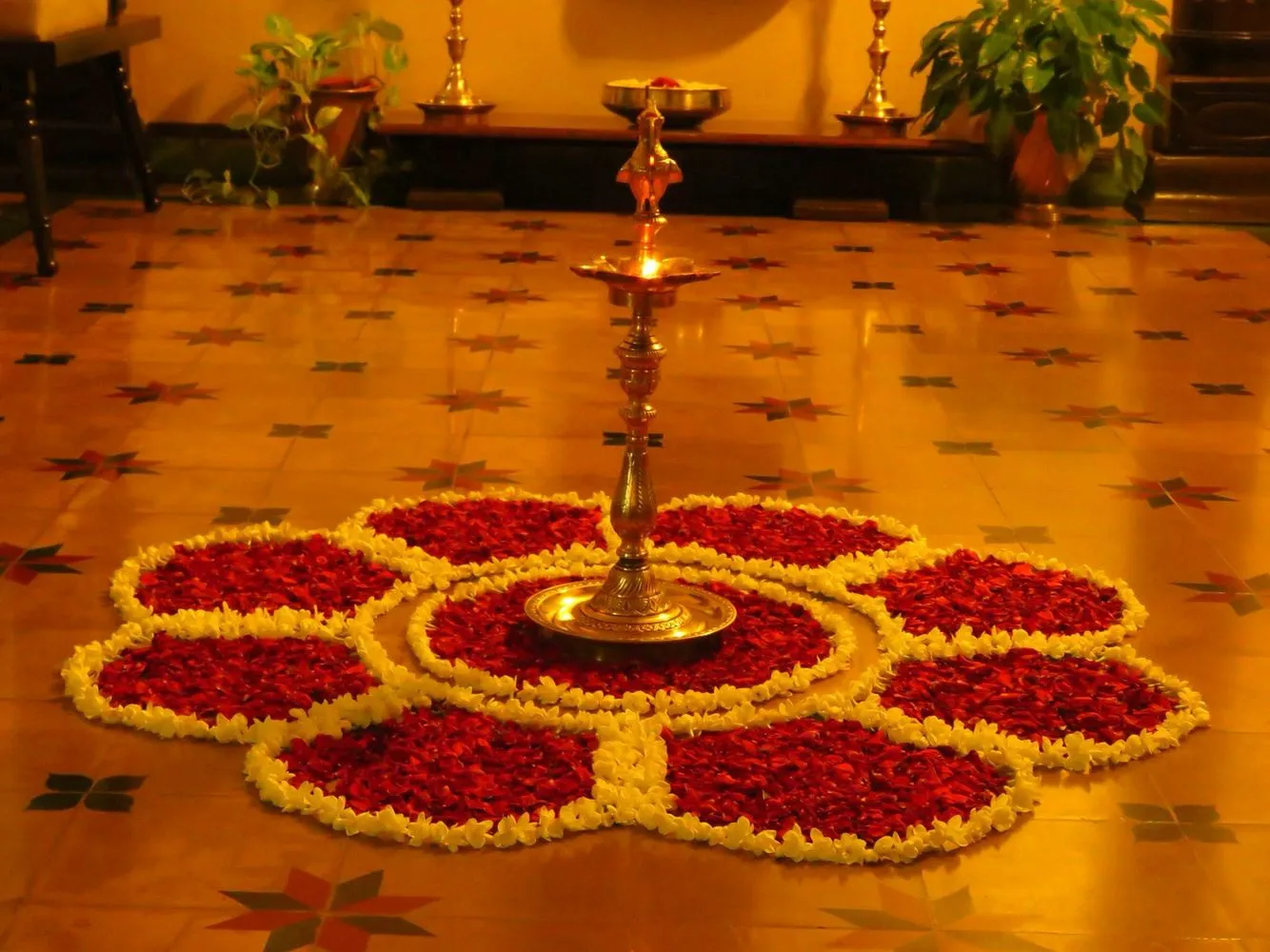 Onam pookolam with lamp and red and white flower petals