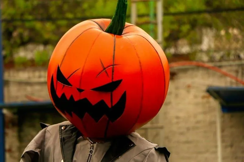 Orange Pumpkin with Angry Face Mask Covering Head Wallpaper
