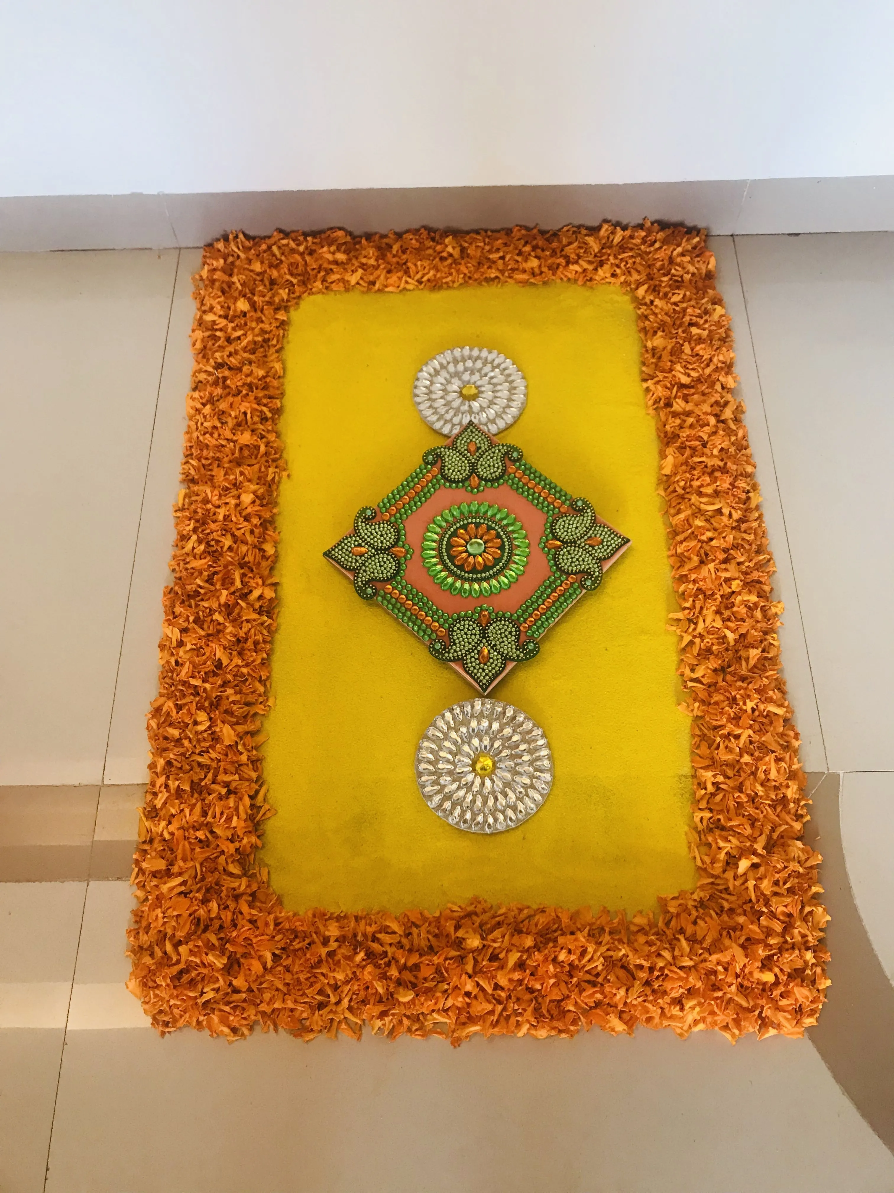 Orange rectangular pookolam with orange and green beads