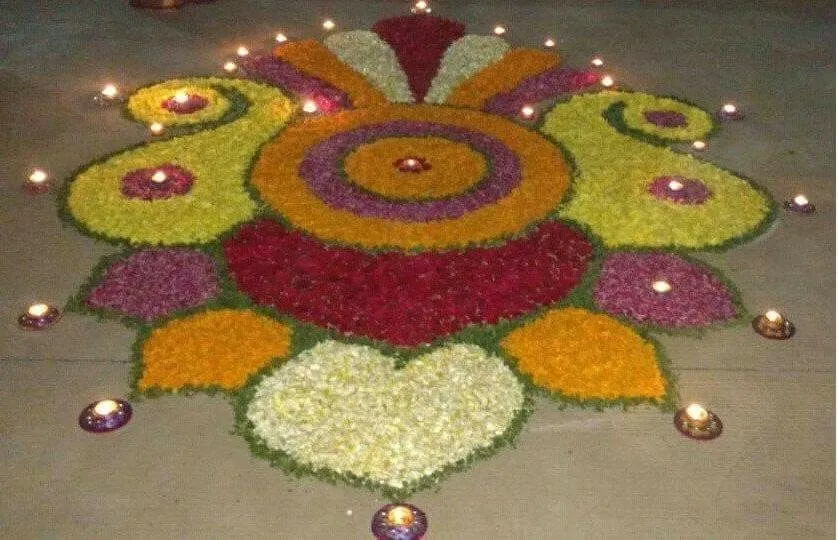 Paisley shaped Onam pookolam with glowing oil lamps image