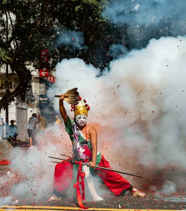 Performer in Colorful Costume Amidst Smoke and Fireworks