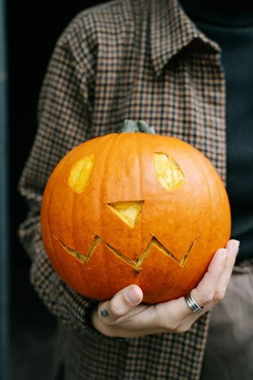 Person Holding Bright Carved Pumpkin in Hands Wallpaper