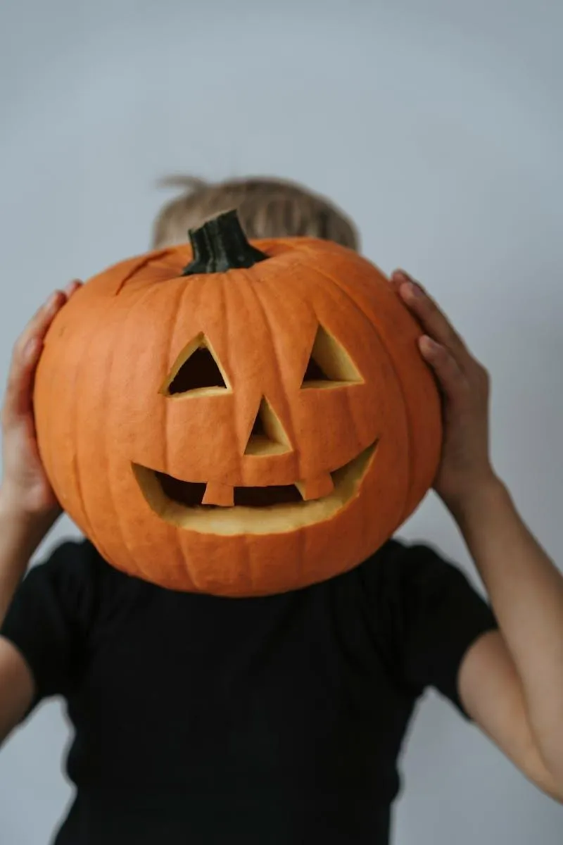 Person holding pumpkin head with a large grin for Halloween