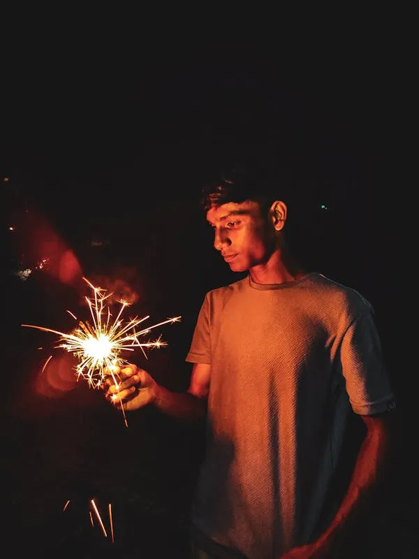 Person Holding Sparkler Creating Bright Light Trails
