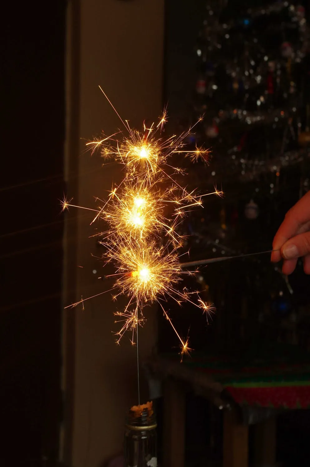 Person Holding Sparkler with Blurred Fireworks image