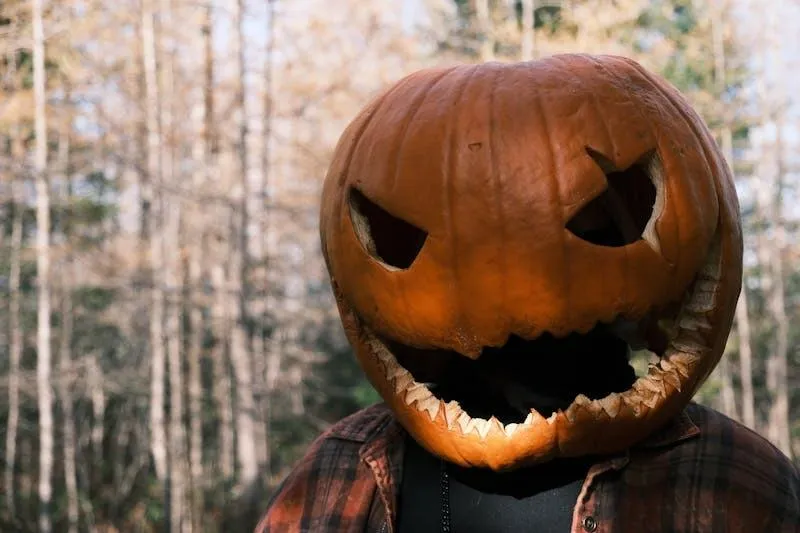 Person in a pumpkin head costume at Halloween festival