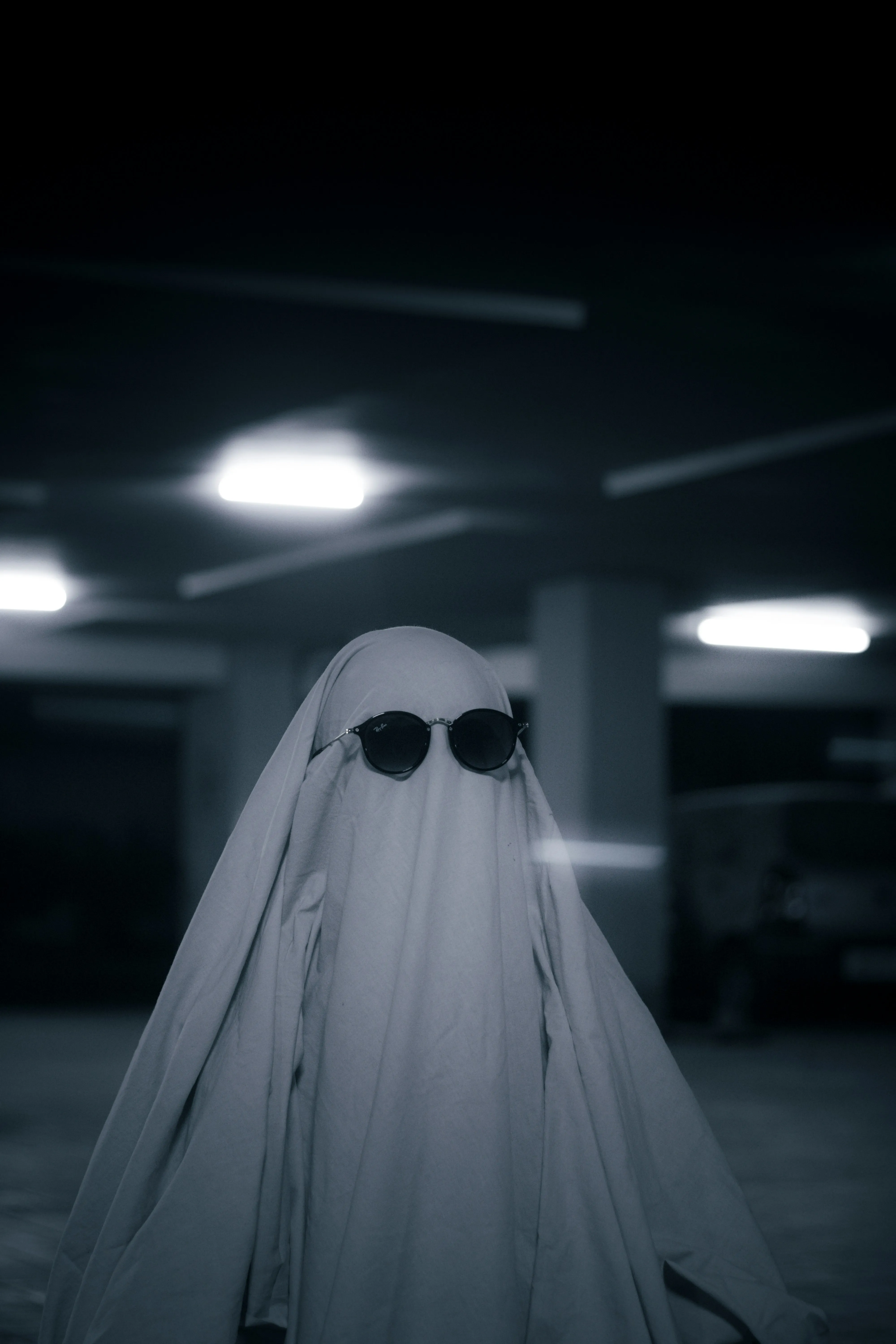 Person in Ghost Costume with Sunglasses in Parking Garage
