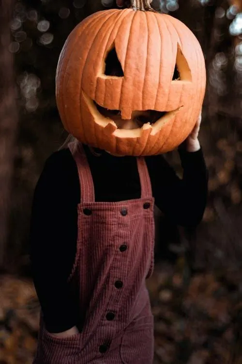 Person in Pumpkin Head Costume with hands in pocket