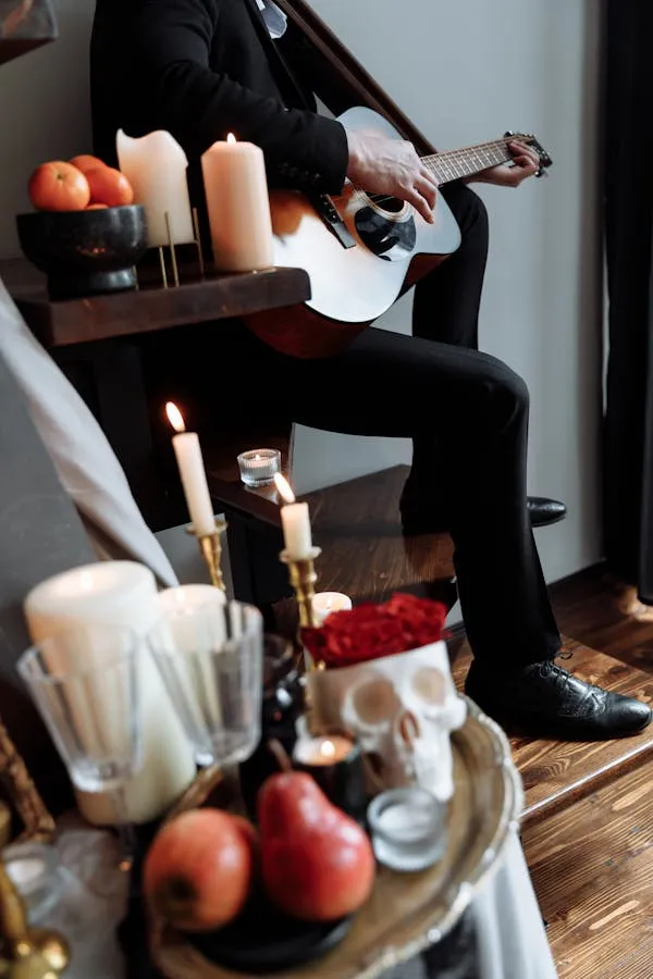 Person playing guitar with a skull and candles on the stairs