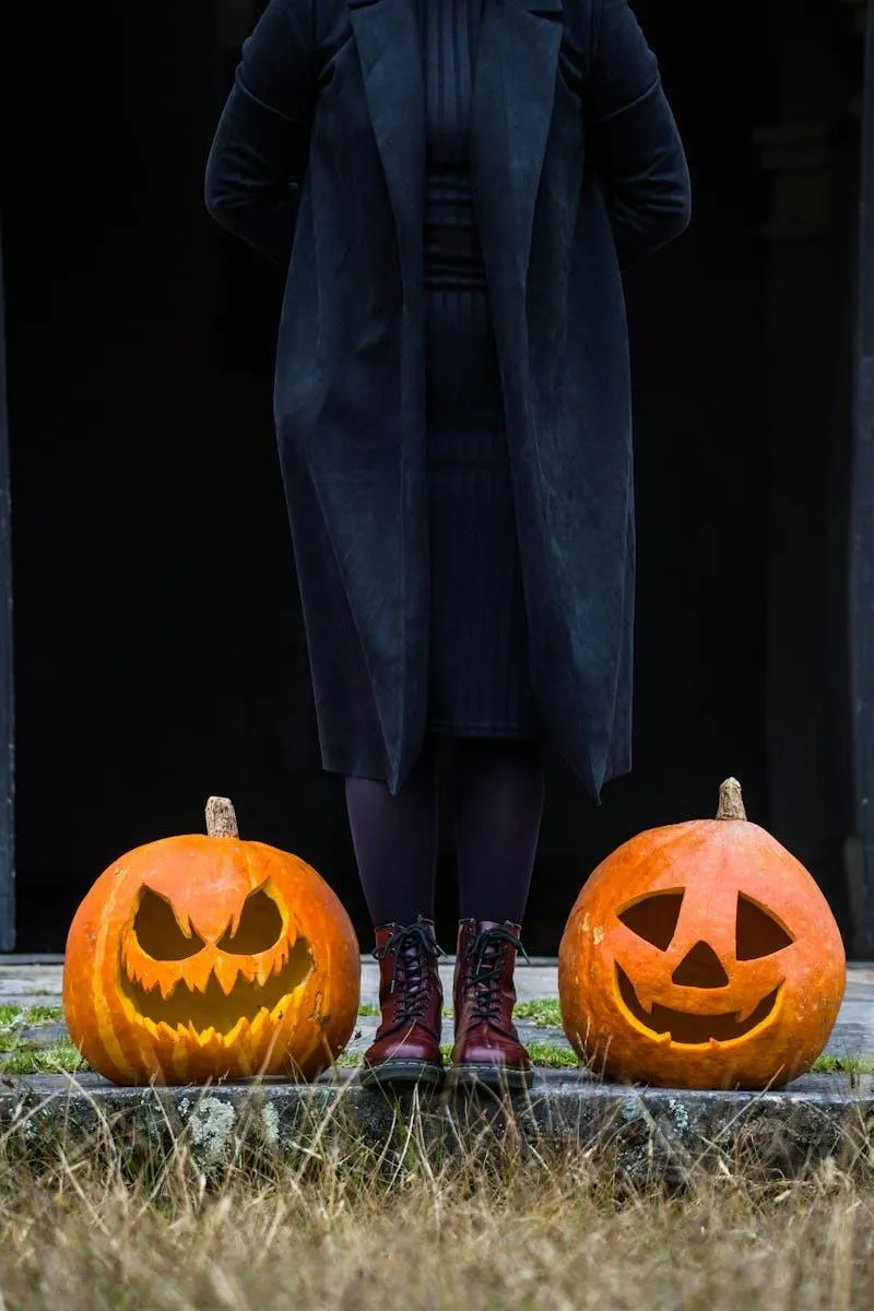 Person Standing Near Two Jack O Lanterns in a Field at Dusk