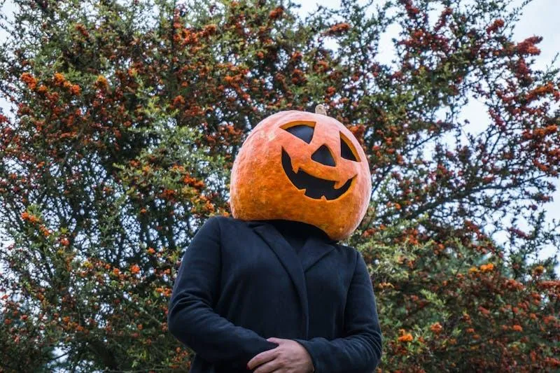 Person Wearing Pumpkin Head Costume in Nature Setting