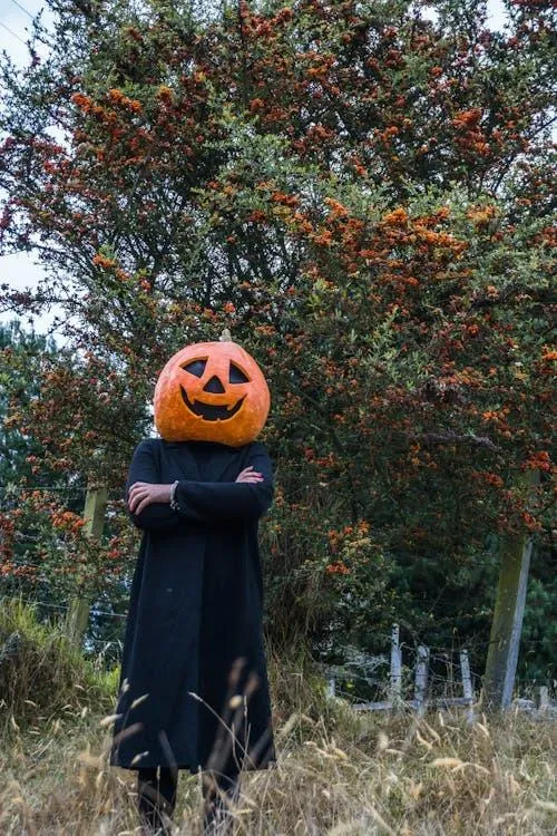 Person Wearing Pumpkin Head in Autumn Forest with cross arms