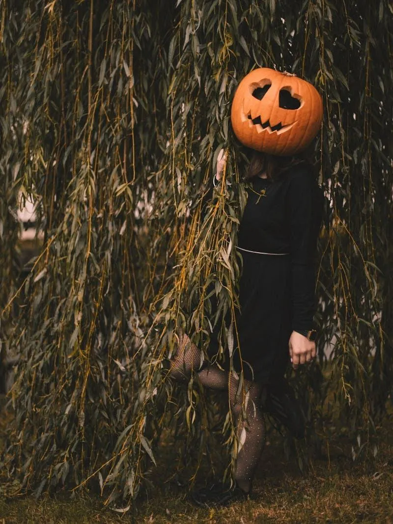 Person Wearing Pumpkin Head in Forest Near Tall Grass