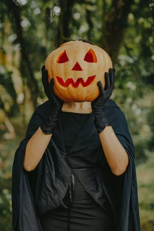 Person with Pumpkin Head and Black Cloak for Halloween