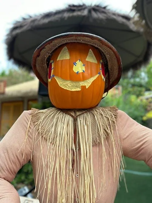 Person with pumpkin head wearing witch hat on Halloween