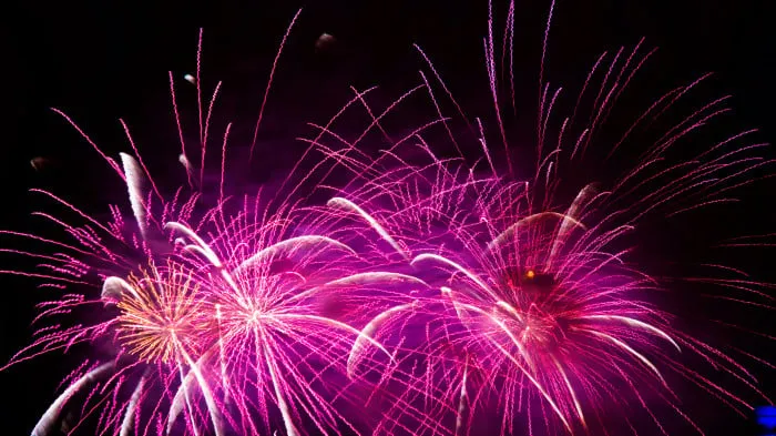 Pink and purple fireworks exploding in a dark sky image