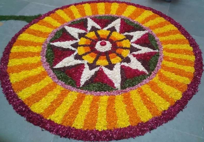 Pink circular rangoli with orange and yellow petal lines