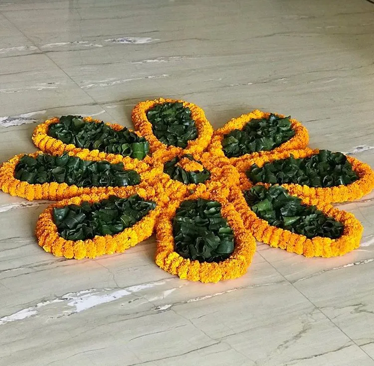 Pookolam with orange marigold border filled with green leafs