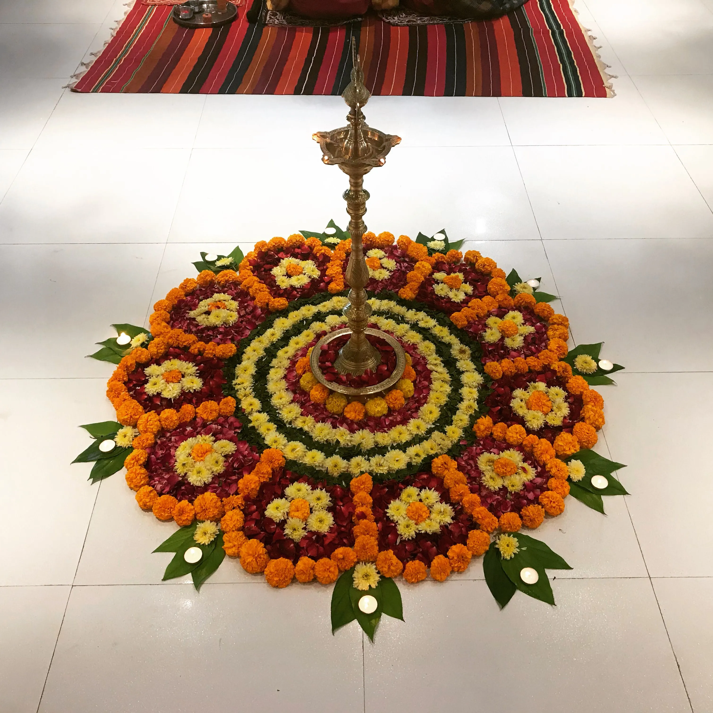 Pookolam with red roses marigolds and leaves with Lamp image