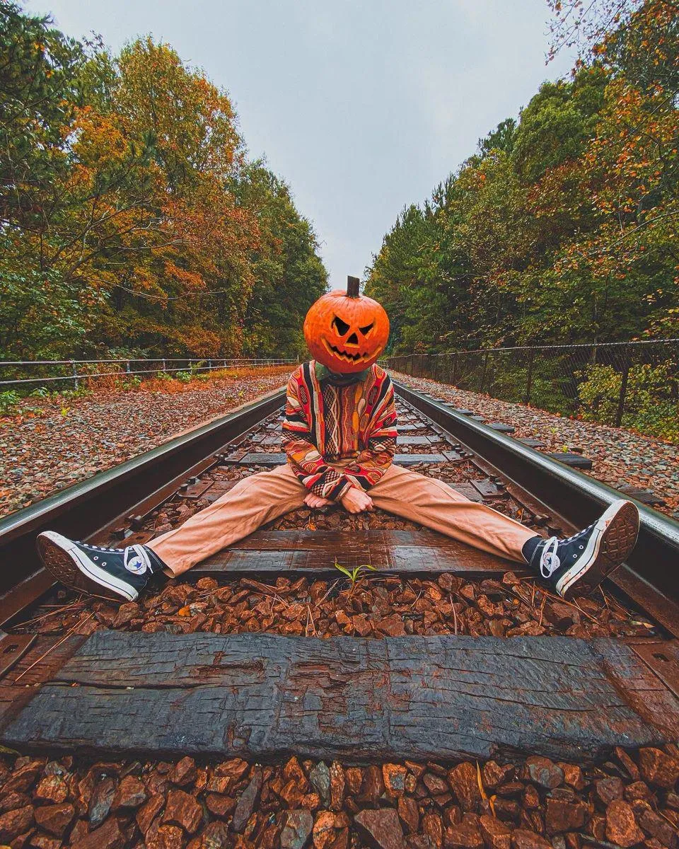 Pumpkin Head Sitting Alone on Empty Railway Track Wallpaper